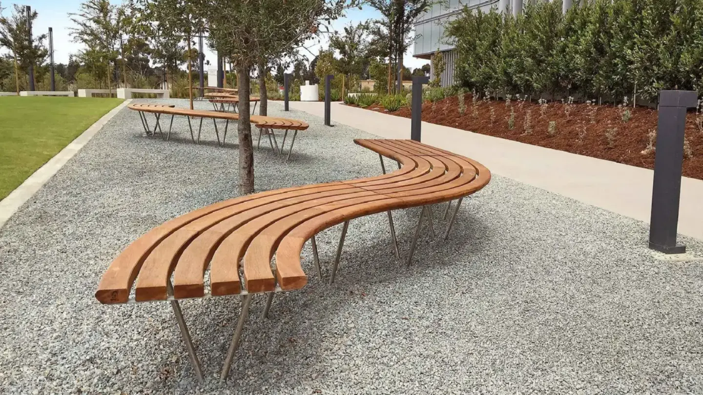 Banc courbe en bois installé sur un parvis pavé